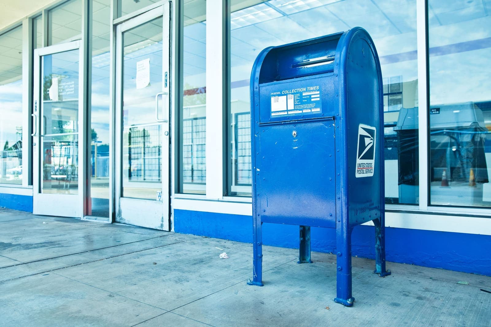 A blue USPS collection box in front of a post office